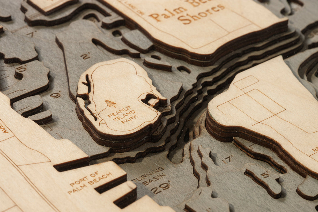 Macro detail of a Woodchart: layered Baltic birch plies, laser-engraved place names and depth soundings