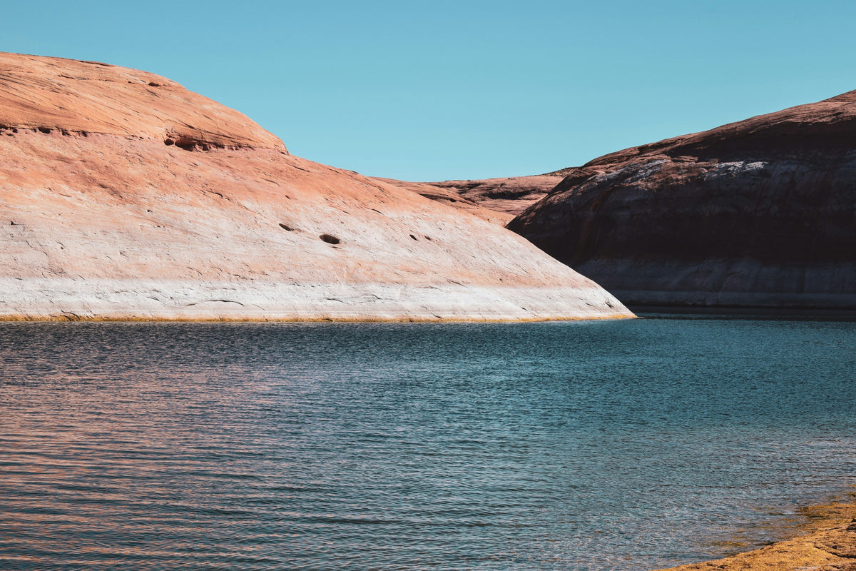Red sandstone cliffs meeting the blue water of Lake Powell in Arizona
