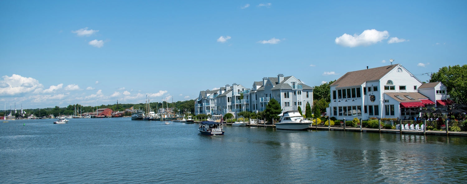 A boat on the Mystic River with the white clapboard waterfront of Mystic, Connecticut behind it