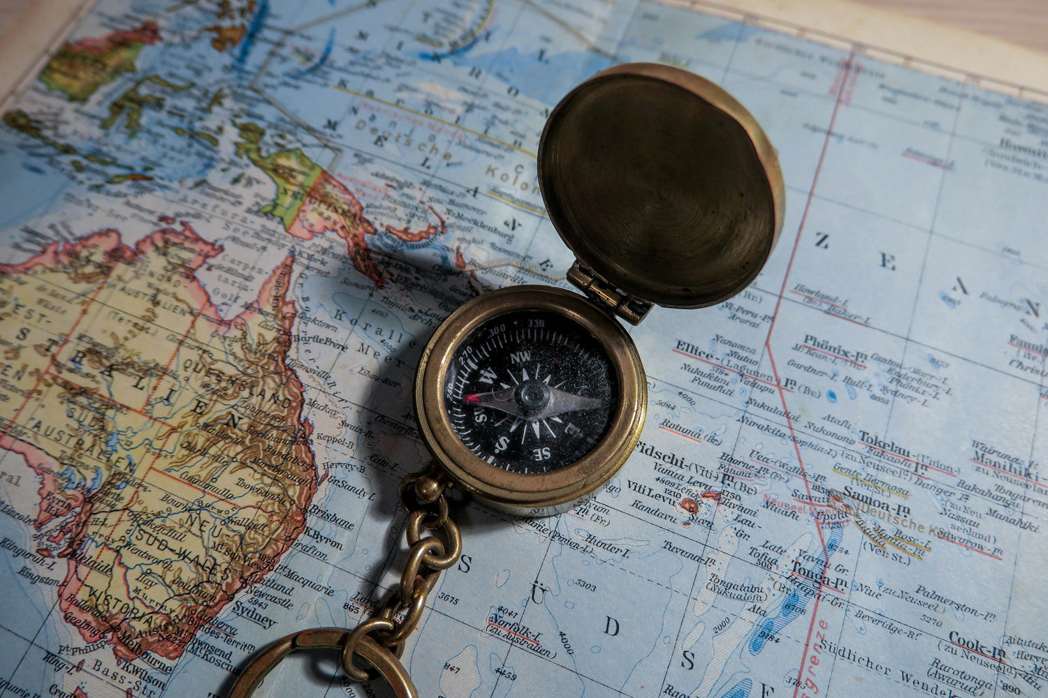 A brass compass resting open on a printed paper map