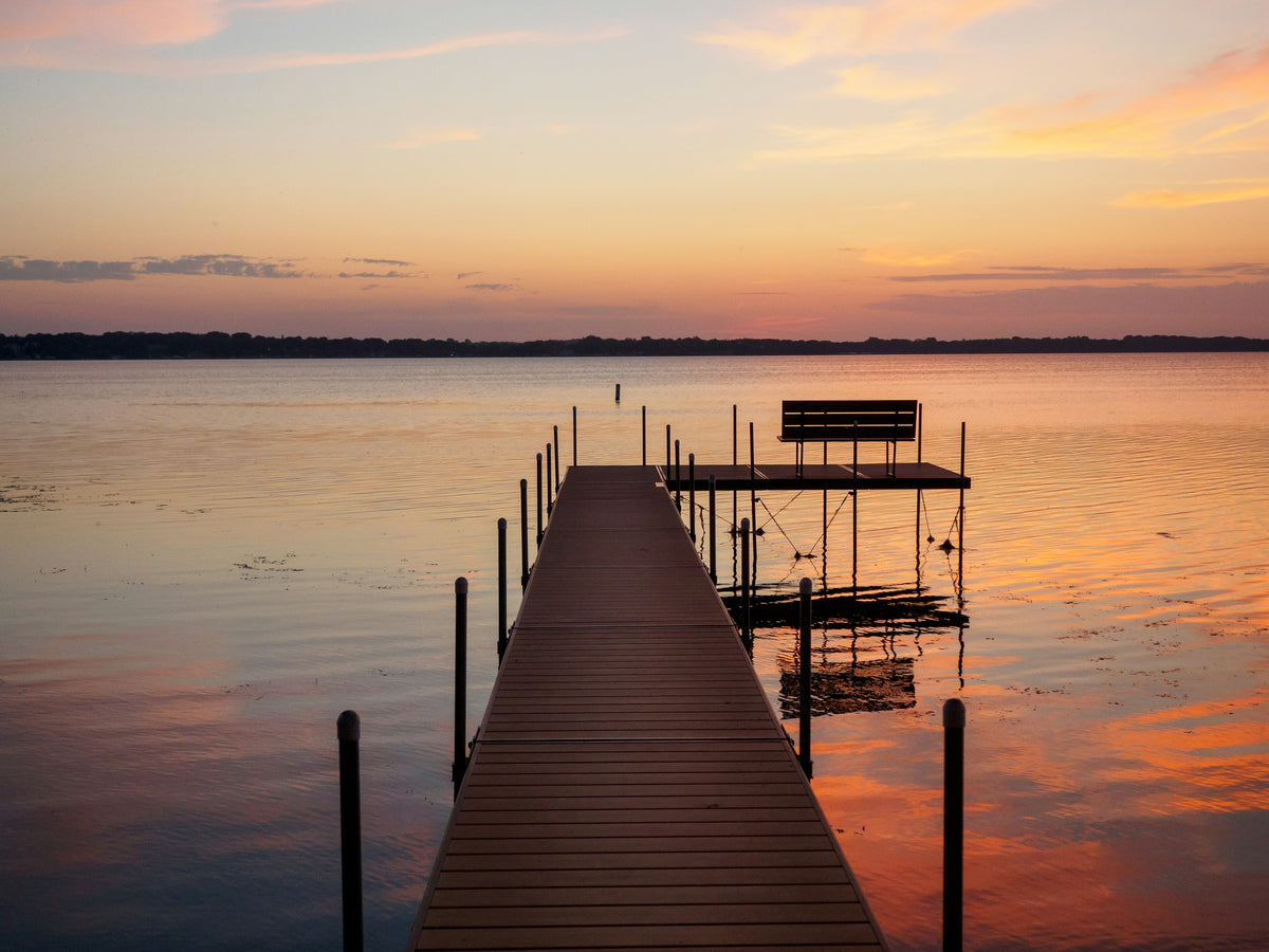 A wooden dock reaching into a calm Iowa lake at sunset
