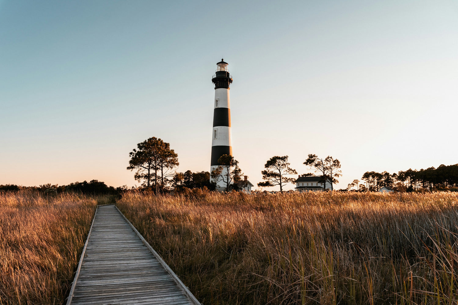Bodie Island Lighthouse rising above marsh grass and a boardwalk on North Carolina's Outer Banks