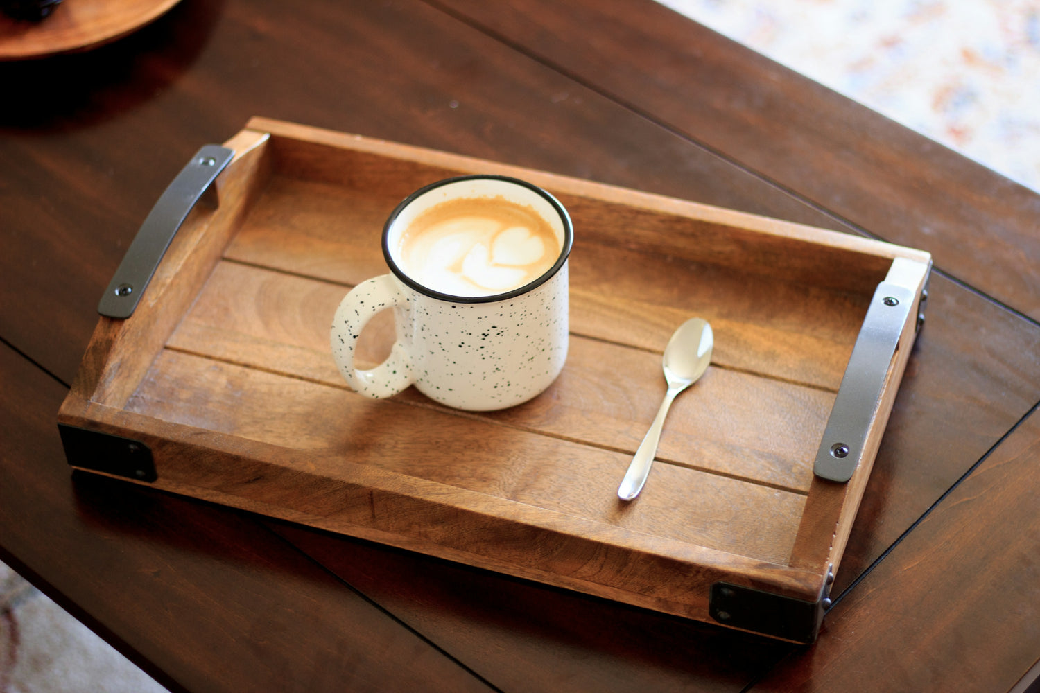 A white ceramic mug and spoon on a wooden serving tray