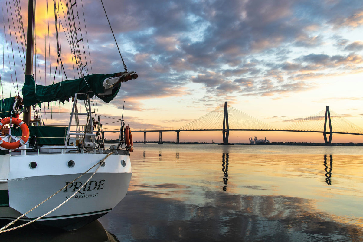 A tall ship docked in Charleston Harbor with the Ravenel Bridge at sunset, South Carolina