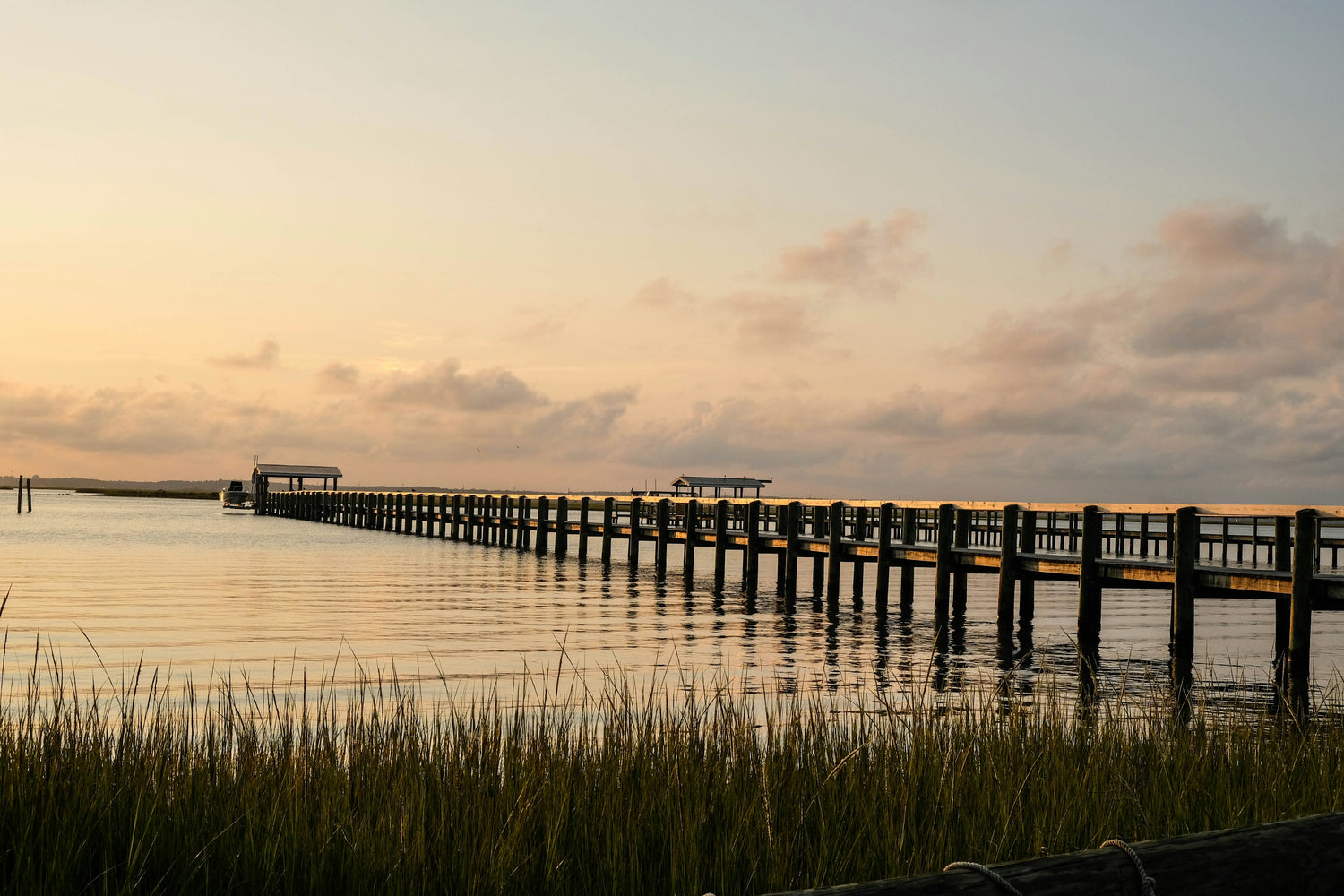 A long wooden dock stretching over calm water at sunset on the Virginia shore